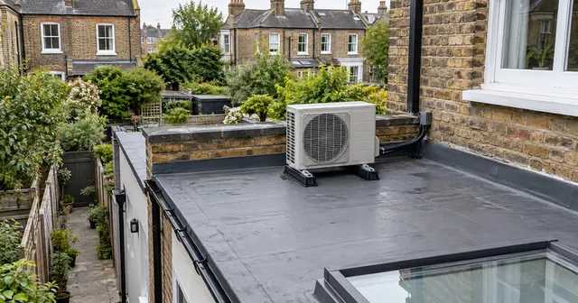 The rear of a London terraced house with an outdoor unit tucked behind the parapet of a flat-roofed extension